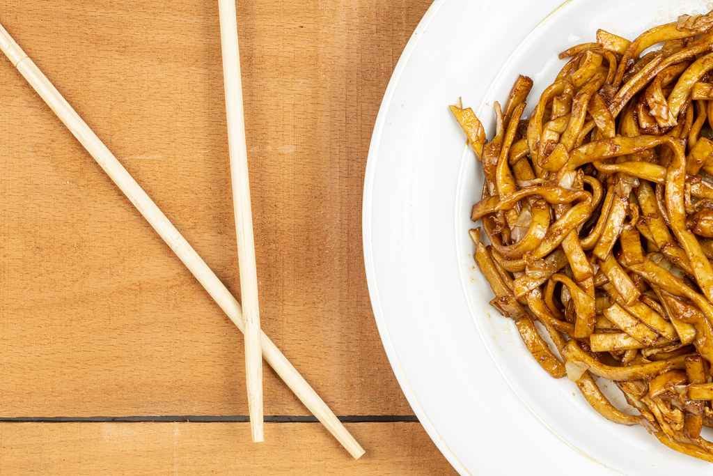 Image of served Chinese food in a plate with chopsticks.